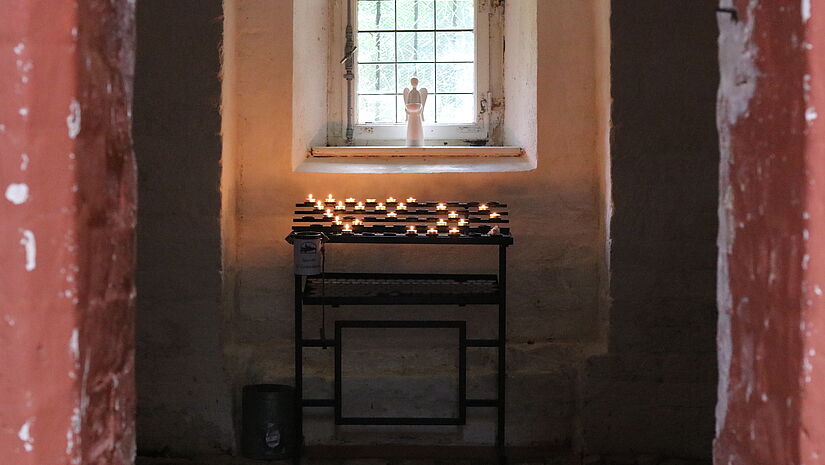 Die Sakristei der Dorfkirche Poel Blick in die Sakristei. Ein Engelsfigur steht im Fenster. Darunter brennen viele Kerzen.