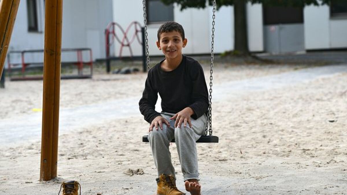 Ein syrisches Flüchtlingskind schaukelt auf dem Spielplatz des Grenzdurchgangslager Friedland in Niedersachsen (epd-Archiv).
