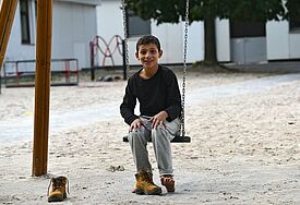 Ein syrisches Flüchtlingskind schaukelt auf dem Spielplatz des Grenzdurchgangslager Friedland in Niedersachsen (epd-Archiv).