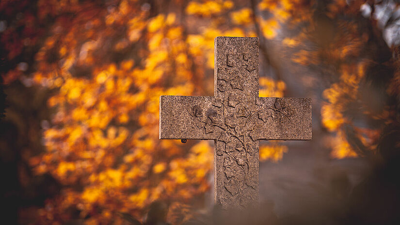 Steinkreuz auf einem Friedhof im Herbstlicht