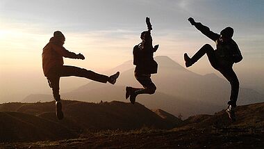 Silhouetten drei junger Menschen, die in die Luft springen