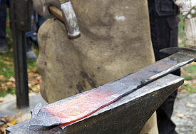 Mit kräftigen Hammschlägen haben zwei Schmiede ein Schwert zu einer Pflugschar umgeschmiedet