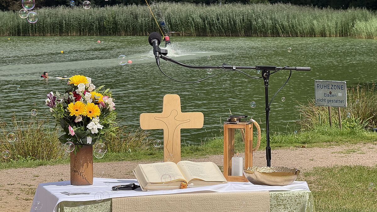 Vorn schweben Seifenblasen, im Hintergrund ziehen Wasserski-Begeisterte ihre Kreise - und mittendrin wird ein Taufgottesdienst gefeiert