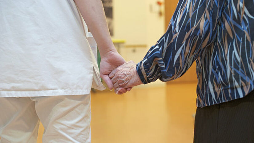 Pflegerin und Bewohnerin im Altenheim, Hand in Hand.