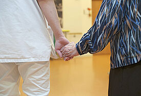Pflegerin und Bewohnerin im Altenheim, Hand in Hand.