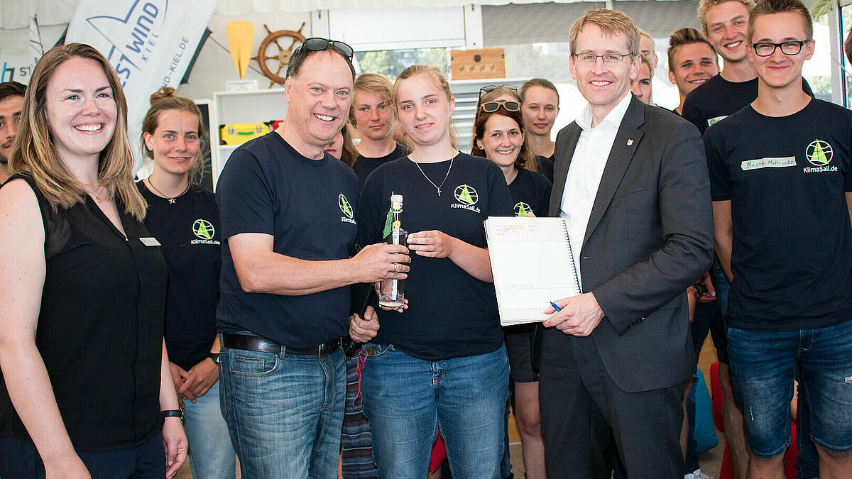 Andreas Tietze, Präses der Landessynode der Nordkirche (3. v.l.), und Ministerpräsident Daniel Günther (4. von r.) zusammen mit Projektteilnehmern und -teilnehmerinnen bei der Kieler Landaktion von KlimaSail.