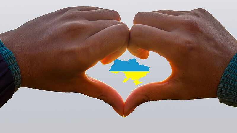Herz aus Händen, in der Mitte Nationalfarben der Ukraine 