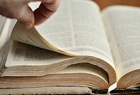 Nahaufnahme einer Bibel, eine Hand blättert um