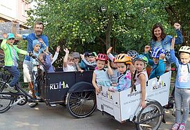 Kinder und Erzieherteam sind begeistert von den umweltfreundlichen Transportmitteln: Erzieherin Anja Seidenkranz und Erzieher Christoph Krumbeck mit den beiden Lastenfahrrädern und zahlreichen fröhlichen Passagieren. Foto: PEK / Sebastian Kühl  