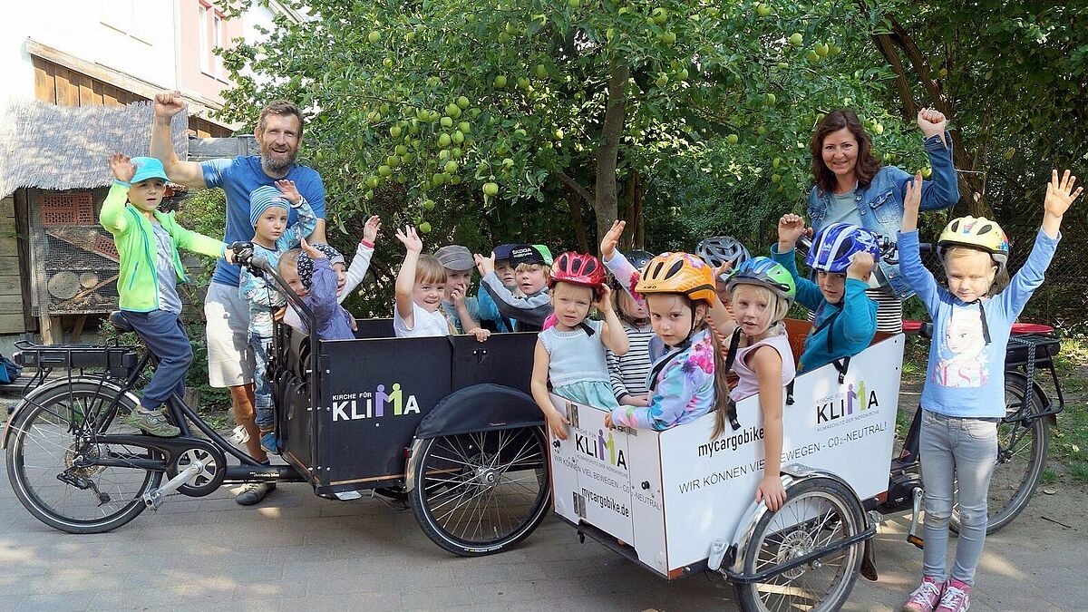 Kinder und Erzieherteam sind begeistert von den umweltfreundlichen Transportmitteln: Erzieherin Anja Seidenkranz und Erzieher Christoph Krumbeck mit den beiden Lastenfahrrädern und zahlreichen fröhlichen Passagieren.