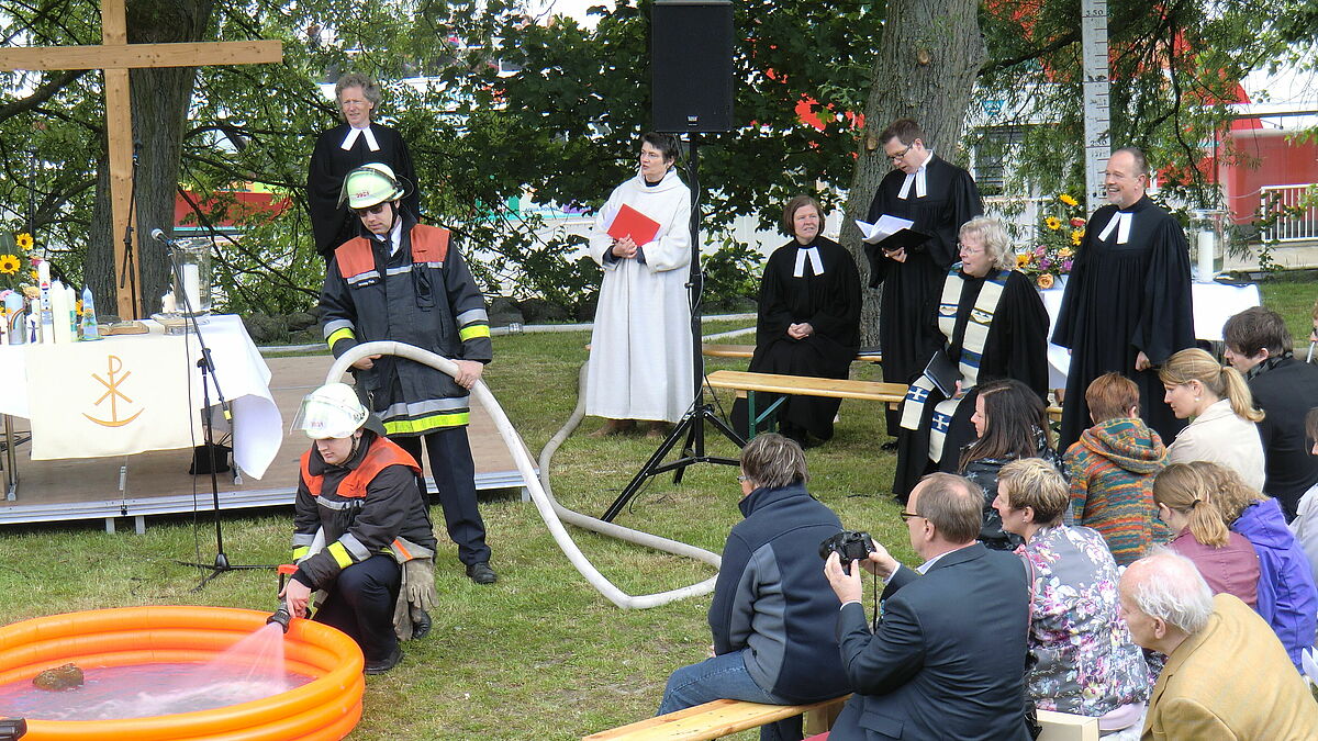 Beim Gottesdienst am Elbanleger in Finkenwerder wird ein Planschbecken zum Taufbecken.