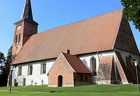 Seitenansicht der Kirche, die weiß verputzt ist und ein Ziegeldach trägt.