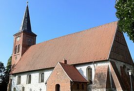 Seitenansicht der Kirche, die weiß verputzt ist und ein Ziegeldach trägt.