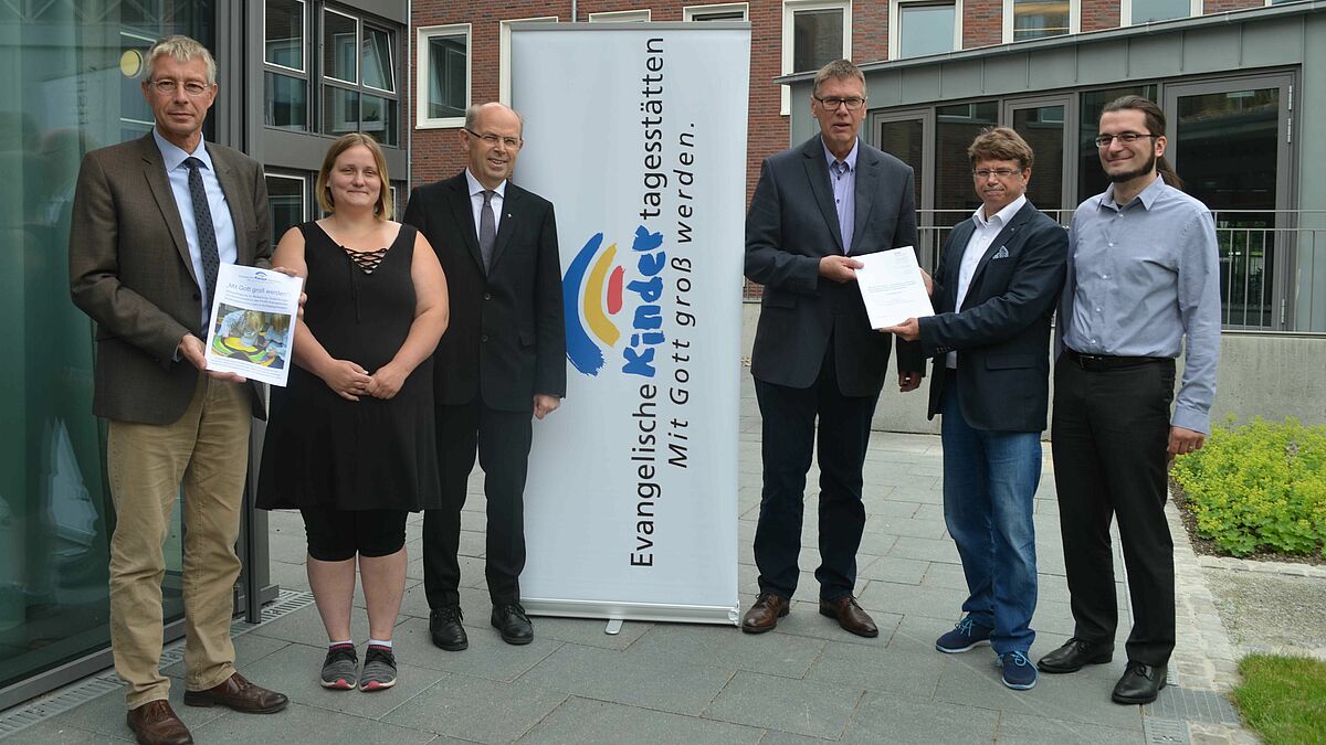 VEK-Vorsitzender Propst Sönke Funck, Kita-Mutter Jessica Nordt, Bischof Gothart Magaard und VEK-Geschäftsführer Markus Potten nehmen die Ergebnisse der Elternbefragung aus den Händen von Prof. Andreas Langer und Henning Kiani (DISW) entgegen. 