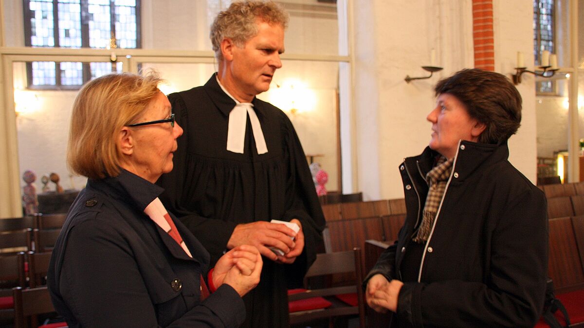 Pastor Dr. Gottfried Timm im Gespräch mit zwei Gottesdienstbesucherinnen