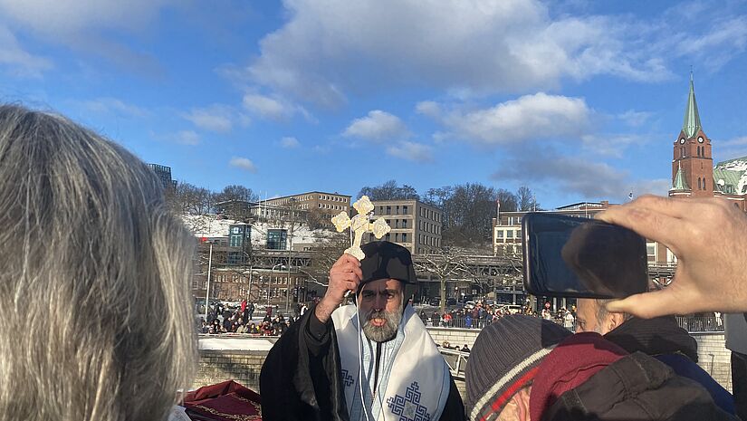 Bischof Bartholomaios bei Orthodoxer Wasserweihe taucht das Kreuz ins Wasser der Elbe