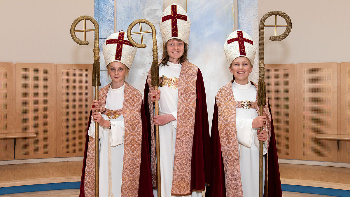 Die drei Kinderbischöfe Luca, Mena und Tim (von links nach rechts) werden in einem Gottesdienst von ihrem Amt entpflichtet. In ihrer Amtszeit haben sie sich für das Recht der Kinder auf Schutz im Krieg und auf der Flucht eingesetzt.