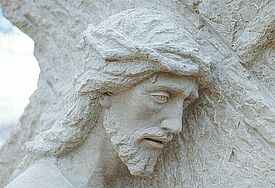 Karfreitag in Stein gemeißelt: Skulptur von Jesus, wie er das Kreuz trägt.