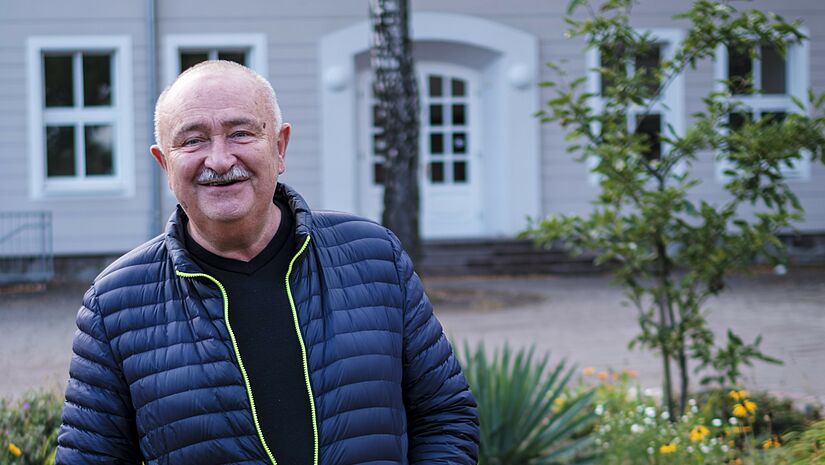 Der Gründer des Evangelischen Bildungscampus Dettmannsdorf Stefan Schmidt steht in herbstlicher Kleidung vor einem Schulgebäude