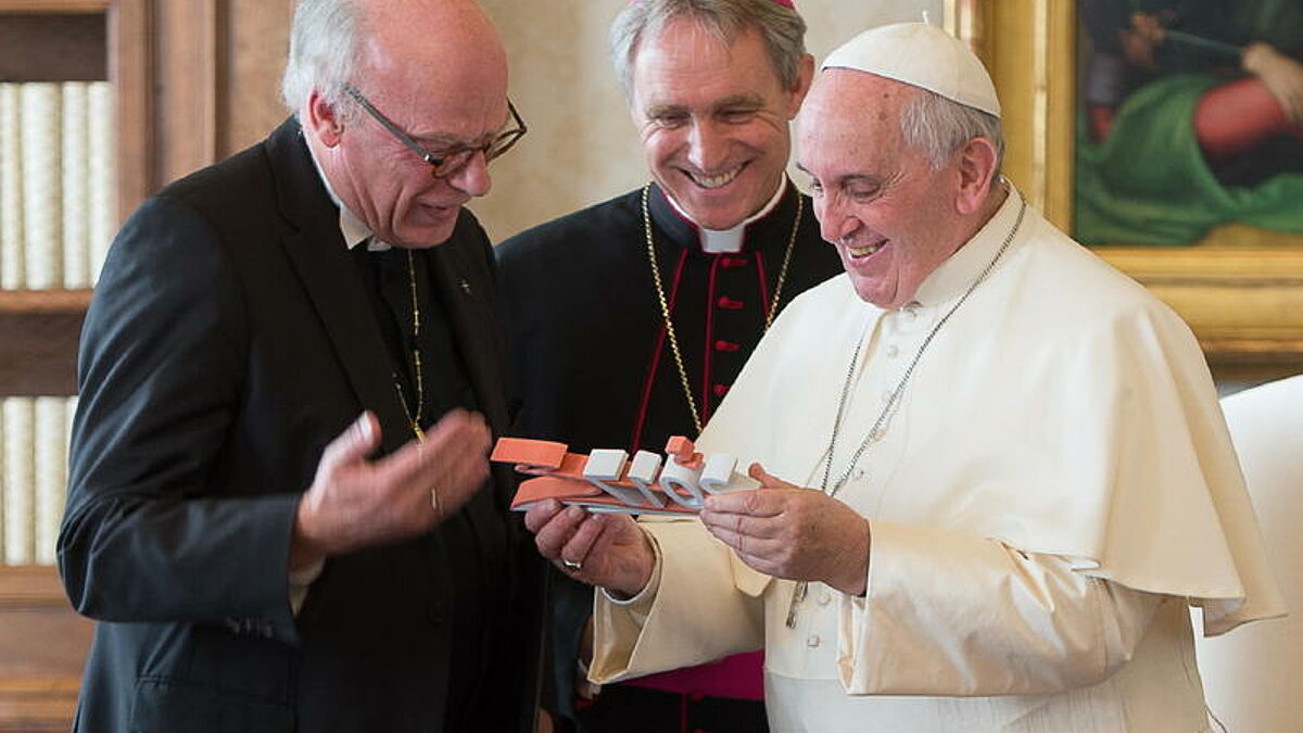 Papst Franziskus hat am Donnerstag (18.12.14) im Vatikan Spitzenvertreter der deutschen Lutheraner in Privataudienz empfangen. Foto: Der Leitende Bischof der Vereinigten Evangelisch-Lutherischen Kirche Deutschlands (VELKD), Nordkirchenbischof Gerhard Ulrich (l.), uebergibt Papst Franziskus als Gastgeschenk eine kleine Statue mit dem Logo "2017 gemeinsam unterwegs". Gefertigt wurde sie von Studierenden des Studiengangs Produktdesign der Hochschule Hannover. Im Jahr 2017 jahrt sich die Reformation zum 500. Mal. Bildmitte Kurienerzbischof Georg Gänswein. (Siehe epd-Meldung vom 18.12.14)