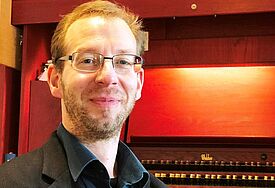 Mann im Hemd und Sakko mit Brille, im Hintergrund die Orgel