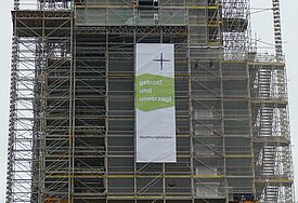 Banner mit der Aufschrift getrost und unverzagt - #hoffnungsläuten hängt am Baugerüst des Kirchturms vom Dom in Schleswig