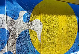 Graffitti zeigt eine Taube, die gen Sonne fliegt in den Farben der Ukraine 