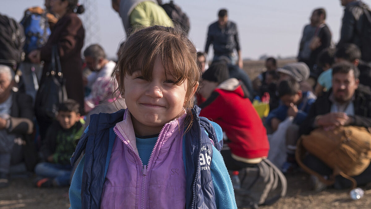 Dobova, Slovenia - October 26, 2015: A group of refugees waits in the fields for the clearance to enter the nearby Dobova refugee camp. It could take up to 4 hours to the previous group of refugees to leave the camp of Dobova, carried on buses toward Austrian border. 