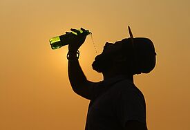Silhouette eines Mannes, der sich Wasser in den Mund kippt