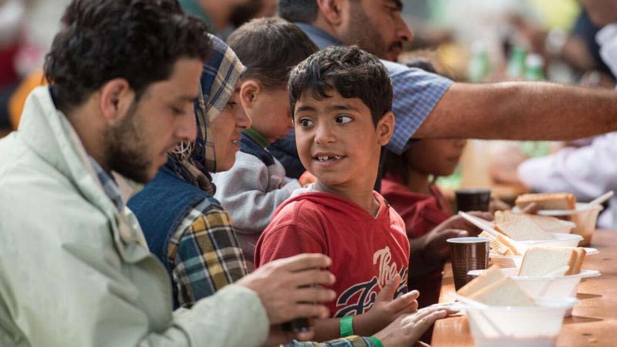 Syrische Flüchtlinge bekommen nach ihrer Ankunft am Hauptbahnhof in München bei einer Registrierungsstelle am Sonntag (13.9.15) etwas zu essen. 200.000 Ehrenamtlcihe helfen in Deutschland in den Kirchengemeinden bei der Versorgung der Flüchtlinge