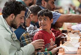 Syrische Flüchtlinge bekommen nach ihrer Ankunft am Hauptbahnhof in München bei einer Registrierungsstelle am Sonntag (13.9.15) etwas zu essen