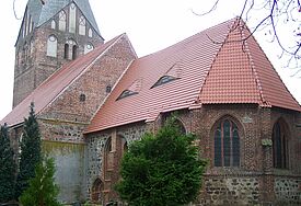 Backsteinkirche, umgeben von kleinen Bäumen und Friedhof