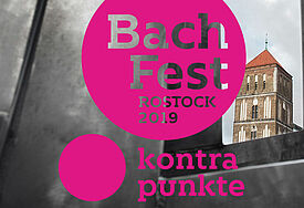 Pinker Kreis mit dem Schriftzug "Bachfest", der über einem Foto von einer Rostocker Kirche liegt.