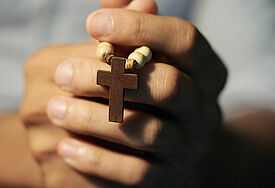 Betende Hände mit Holzkreuz