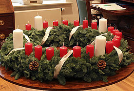 Der Wichern-Adventskranz trägt vier weiße Kerzen für die Adventssonntage und jeweils eine rote Kerze für die anderen Tage bis Weihnachten.