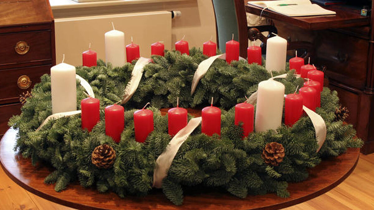 Der Wichern-Adventskranz trägt vier weiße Kerzen für die Adventssonntage und jeweils eine rote Kerze für die anderen Tage bis Weihnachten. 