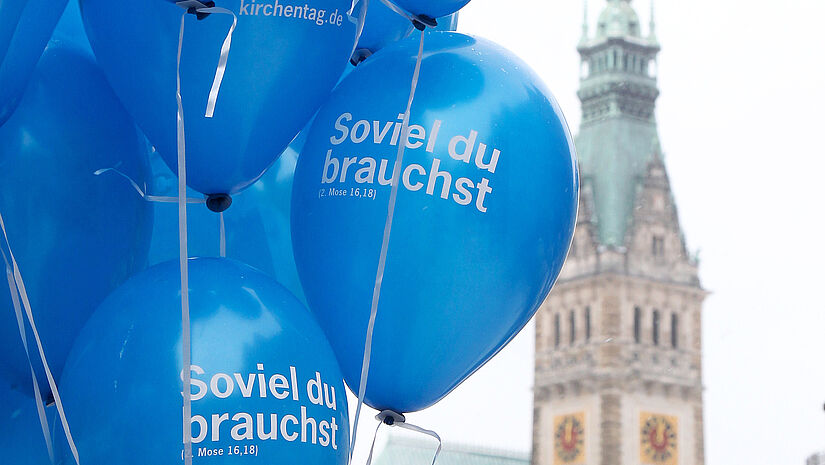 Luftballons mit der Kirchentagslosung "Soviel du brauchst", im Hintergrund das Hamburger Rathaus.