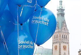 Luftballons mit der Kirchentagslosung "Soviel du brauchst", im Hintergrund das Hamburger Rathaus.