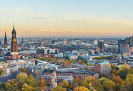 Blick auf Hamburg mit Michel, Hafen und Elbphilharmonie bei Sonnenuntergang.