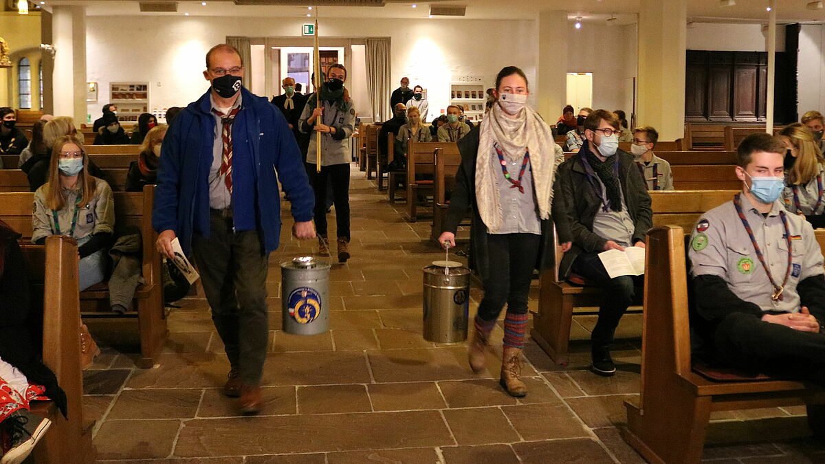 Die Friedenslichtdelegation kommt durch den Mittelgang der Kirche nach vorne