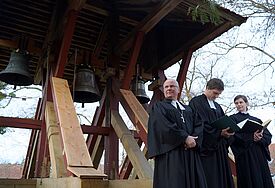 Propst Gerd Panknin (links), Pastor Christian Bauer und Pastorin Katrin Krüger vor den mit Blumen geschmückten Glocken - die historische Glocke hängt links, in der Mitte die neue "Friedensglocke" und rechts die Glocke für "Zuversicht und Stärke"