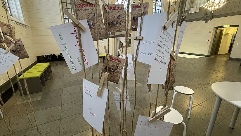 Viele beschriftete Postkarten, die an einem zarten Metallgerüst zum Lesen aufgehängt sind