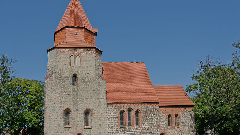 Kirche mit rotem Ziegeldach, umgeben von Grün