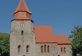 Kirche mit rotem Ziegeldach, umgeben von Grün