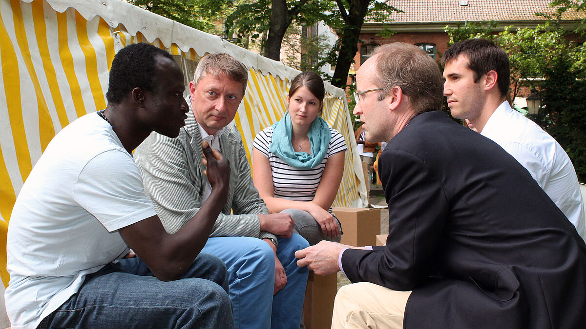 Mitten drin: Constanze Funck ist auch dabei, als sich US-Vizekonsul Robert Stevens (vorne rechts) mit Andreas, dem Sprecher der Flüchtlings-Gruppe, unterhält. Der Ghanaer berichtet, wie er nach Hamburg kam und beschreibt, welche Hilfe er sich erhofft.