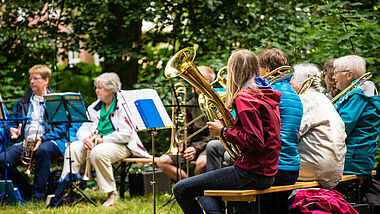Mitglieder eines Posaunenchores sitzen im Kreis beim Kirchengemeindefest.