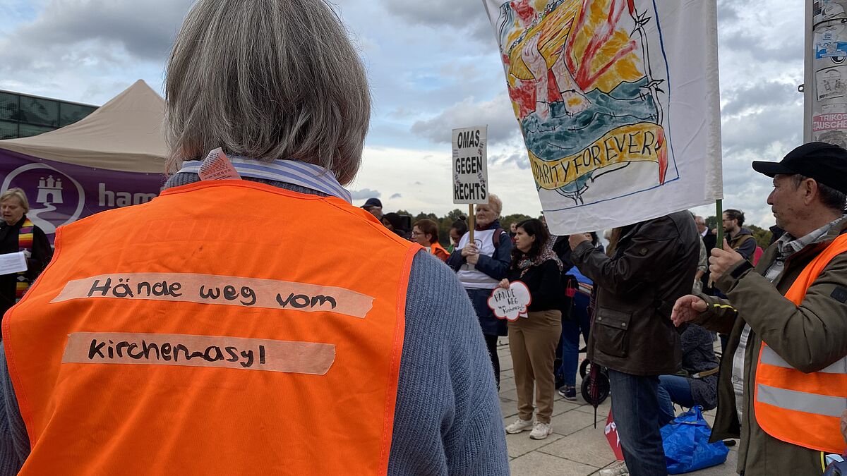 Mahnwache für Kirchenasyl Teilnehmerin mit Weste in Hamburger Innenstadt Das Kirchenasyl ist ein Politikum. Aktuell gibt es nur wenige Menschen, die auf dem Gebiet der Nordkirche im Kirchenasyl leben. Denn die Bedingungen für Geflüchtete und Helfende sind nicht einfach durchzuhalten, sagt unsere Flüchtlingsbeauftragte. Das Bild zeigt eine Demo für den Erhalt des Kirchenasyls (Archivbild).