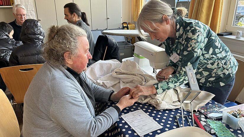 Eine Ehrenamtliche repariert einen Bademantel 