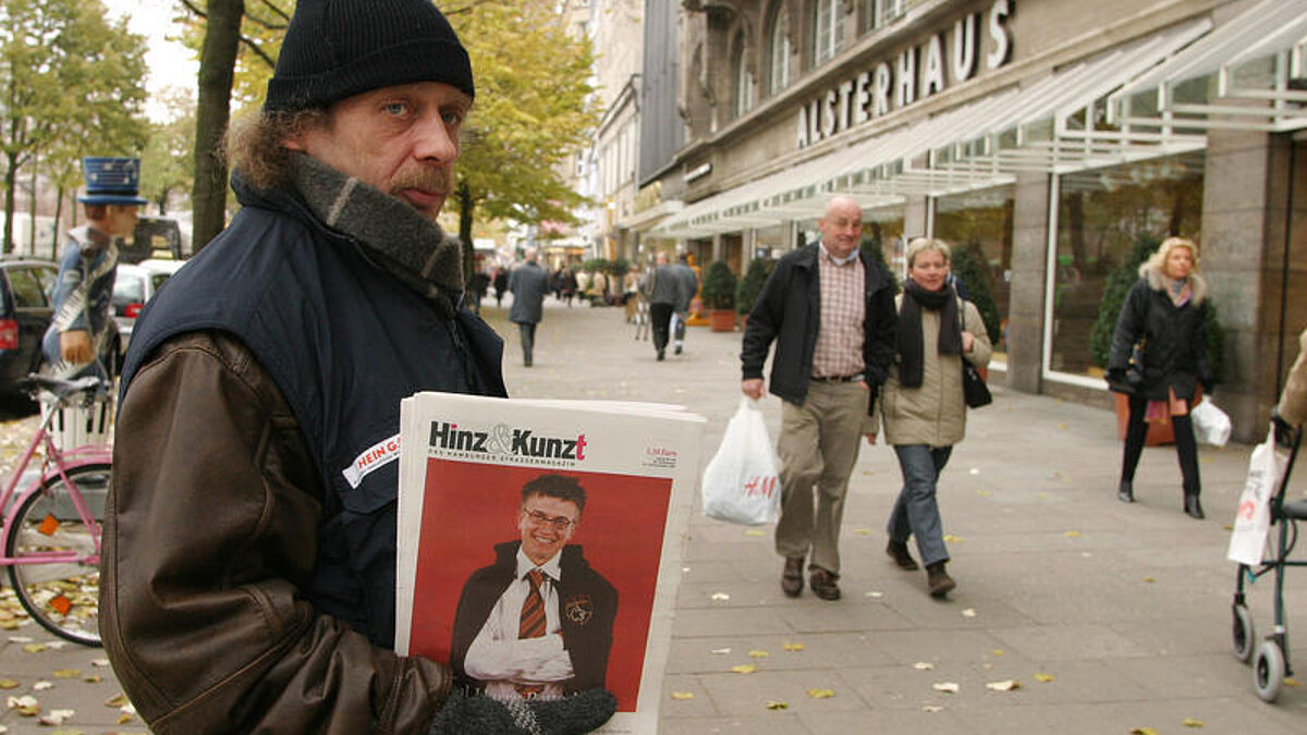 Der Verkäufer der Hamburger Obdachlosenzeitung Hinz und Kunzt Harald bietet auf dem Jungfernstieg in Hamburg Passanten die Zeitung zum Kauf an. Obdachlose in Hamburg können ihre eigenen Unternehmer sein - wenn sie "Hinz & Künztler" sind. Für Die Obdachlosenzeitschrift "Hinz&Kunzt" wurde von der "Patriotischen Gesellschaft" mit gegründet