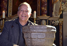 Stolz präsentiert Pastor Torsten Krause das 500 Jahre alte Weihwasserbecken